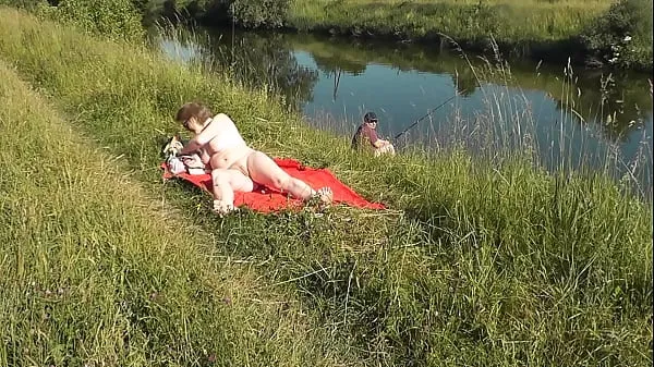 Fresh MILF sexy Frina on river bank undressed and sunbathes naked. Random man fisherman watching for her, and in the end decided to join naked woman. Wild beach. Nudist beach. Public nudity. Public exposure. Naked in public new Movies